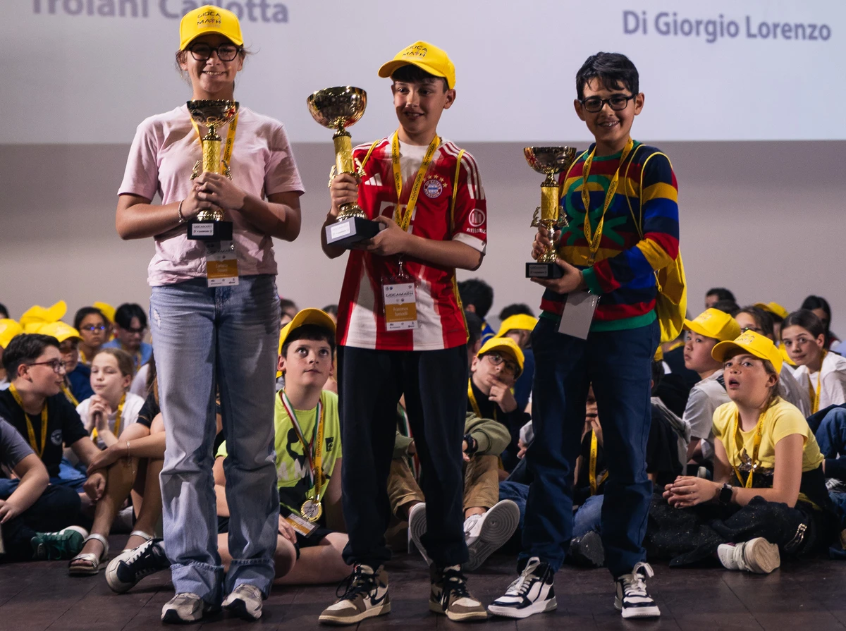 Studenti con coppe e cappellini gialli alla premiazione GiocaMath 2026